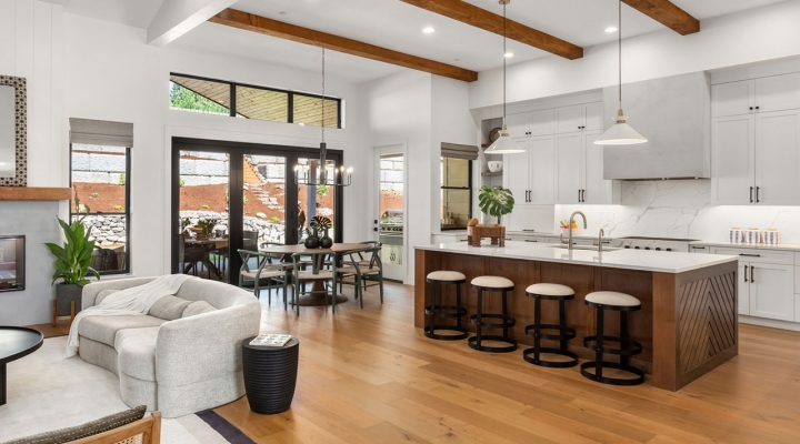 Expansive open plan living area featuring high ceilings with wooden beams, large windows, and a blend of rustic and modern decor elements.