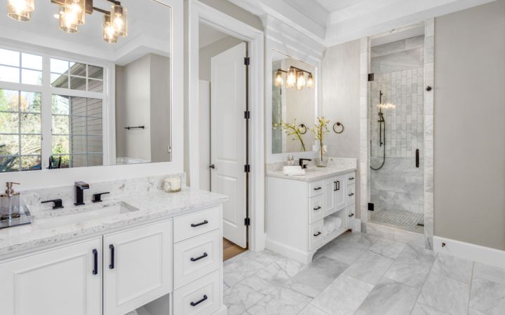 Elegant bathroom design with white marble vanities, a glass-enclosed shower, and chic lighting fixtures creating a bright and luxurious atmosphere.