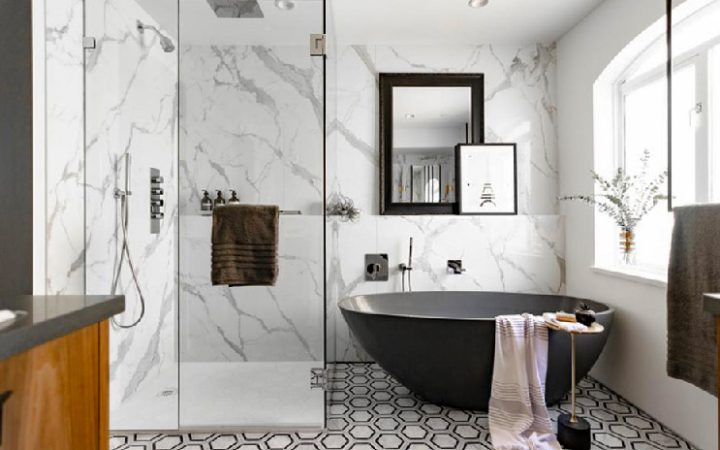 Elegant bathroom featuring a black freestanding bathtub against a dramatic marble wall, complemented by geometric floor tiles and natural wood accents.