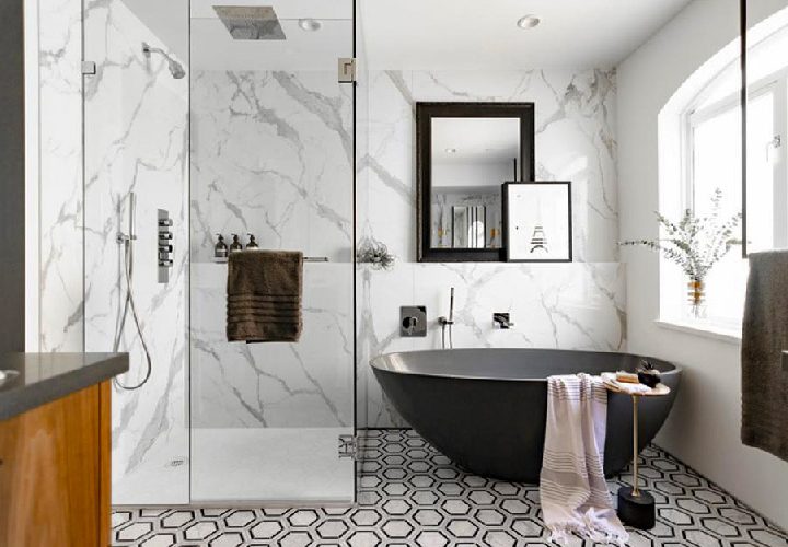 Elegant bathroom featuring a black freestanding bathtub against a dramatic marble wall, complemented by geometric floor tiles and natural wood accents.