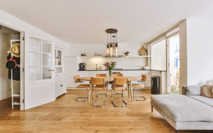 Modern dining and living area with a minimalist design, featuring wooden furniture, large windows, and a spacious layout that maximizes natural light.