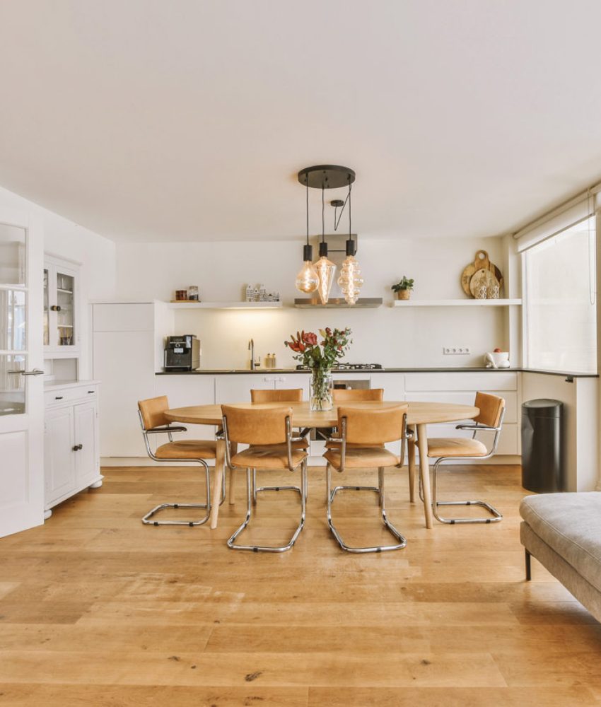 Modern dining and living area with a minimalist design, featuring wooden furniture, large windows, and a spacious layout that maximizes natural light.